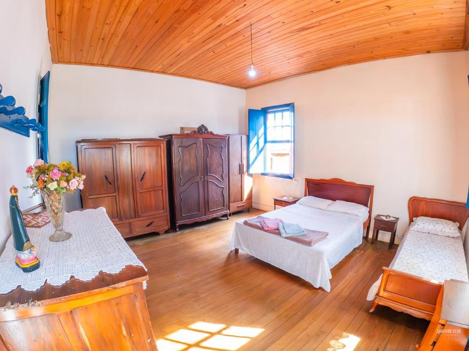 Quarto amplo com cama de casal e de solteiro, guarda-roupas antigos e piso de tábuas corridas
